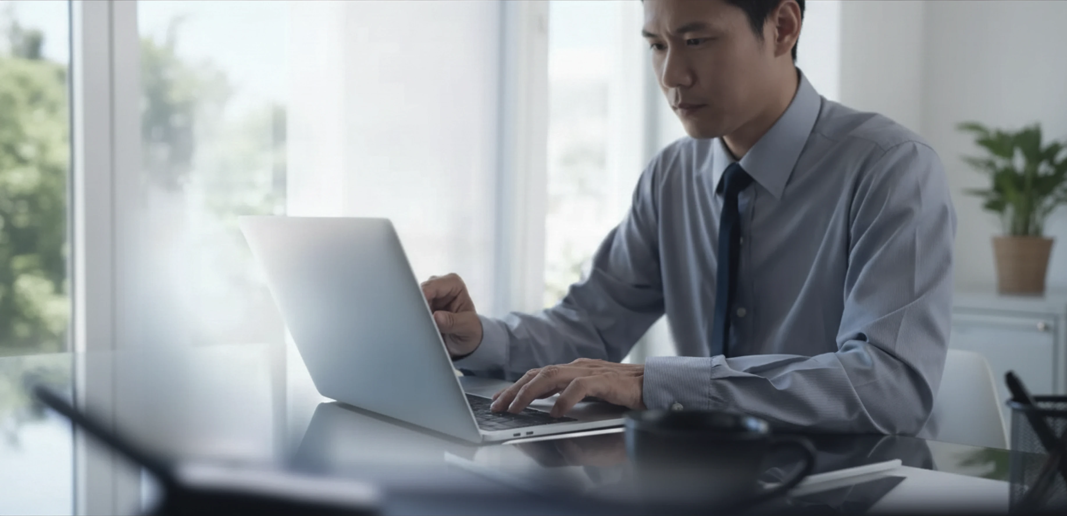 明るいオフィスでノートパソコンを操作する男性ビジネスパーソン