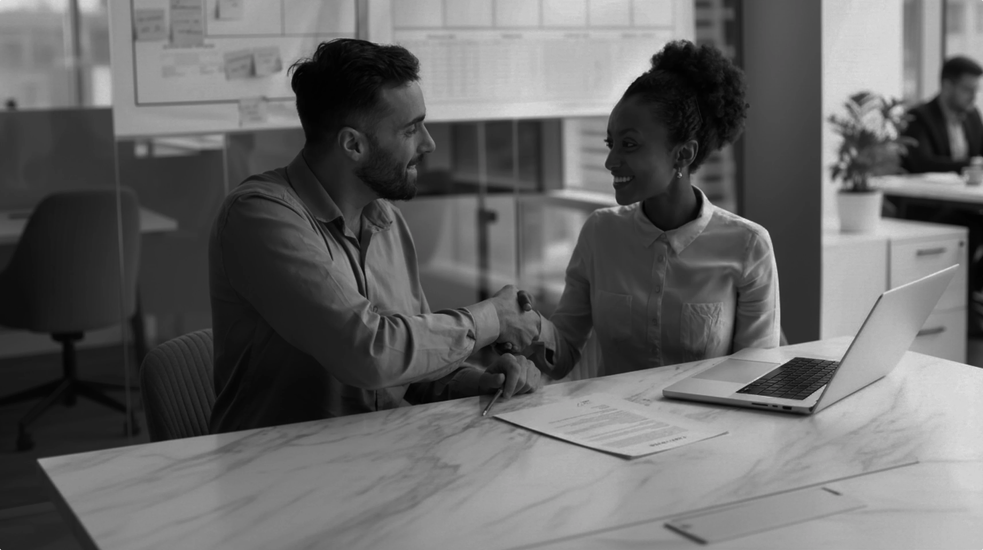 オフィスで笑顔で握手を交わす男女のビジネスパーソン