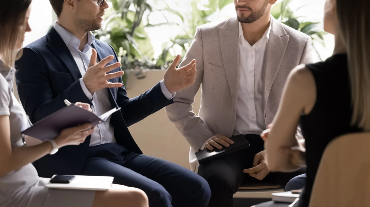 4人のプロフェッショナルが会議で話し合い、メモを取りながら協力する様子