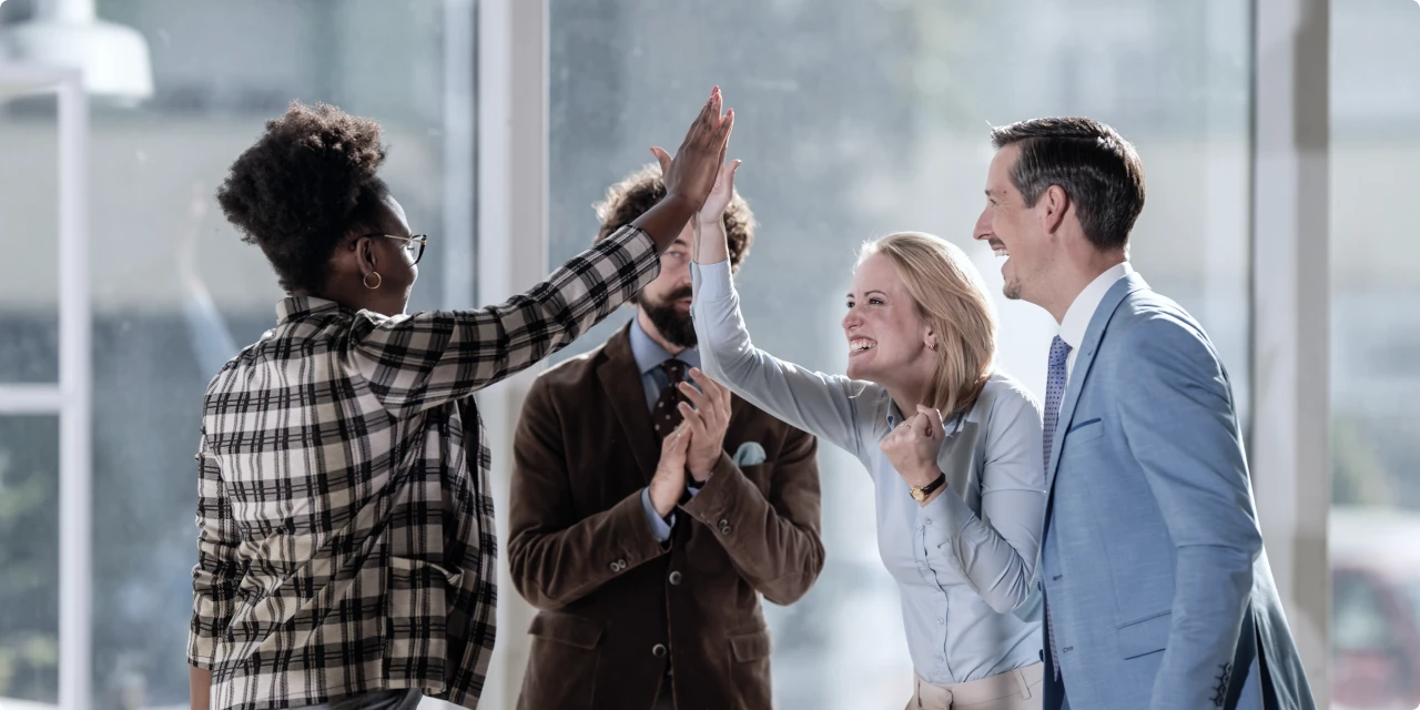 オフィスでハイタッチを交わす4人のチームメンバー