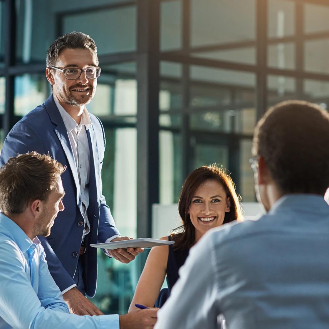 タブレットを持ってチームミーティングをリードするビジネスパーソン