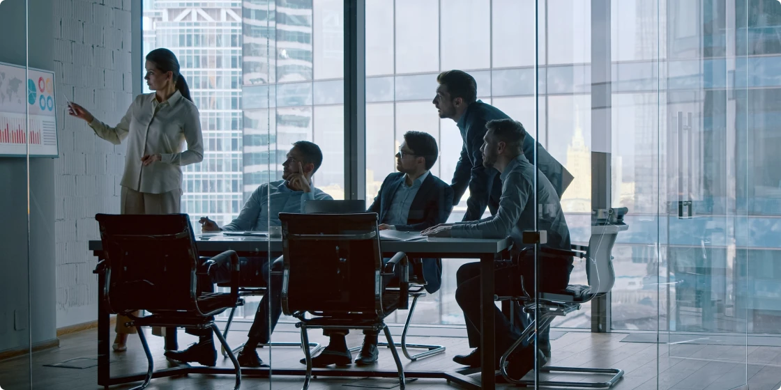 高層ビルが見える会議室でプレゼンテーションを行うチーム